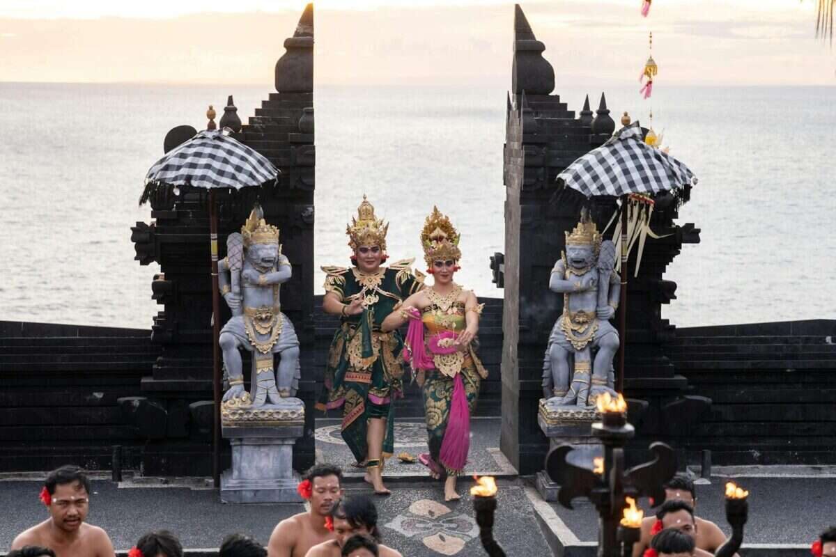 Balinese dancers perform at the iconic Uluwatu Temple during sunset, showcasing vibrant traditional attire.