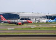 AirAsia plane preparing for takeoff at a bustling airport terminal. Perfect for travel-themed projects.