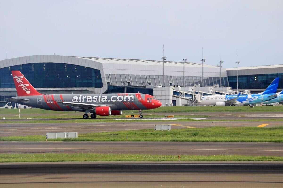 AirAsia plane preparing for takeoff at a bustling airport terminal. Perfect for travel-themed projects.