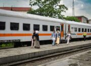 Group of adults walking beside a train at a platform in Bandung, Indonesia, outdoors during the day.