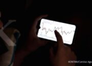 Grafik pergerakan harga aset kripto dan antarmuka aplikasi trading digital di layar laptop