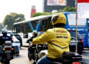 Seorang pengemudi ojek online Maxim sedang melayani penumpang di jalan raya Jakarta.