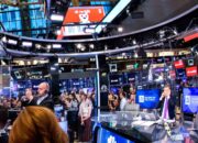 Layar monitor menampilkan grafik pergerakan indeks saham Wall Street yang sedang menguat