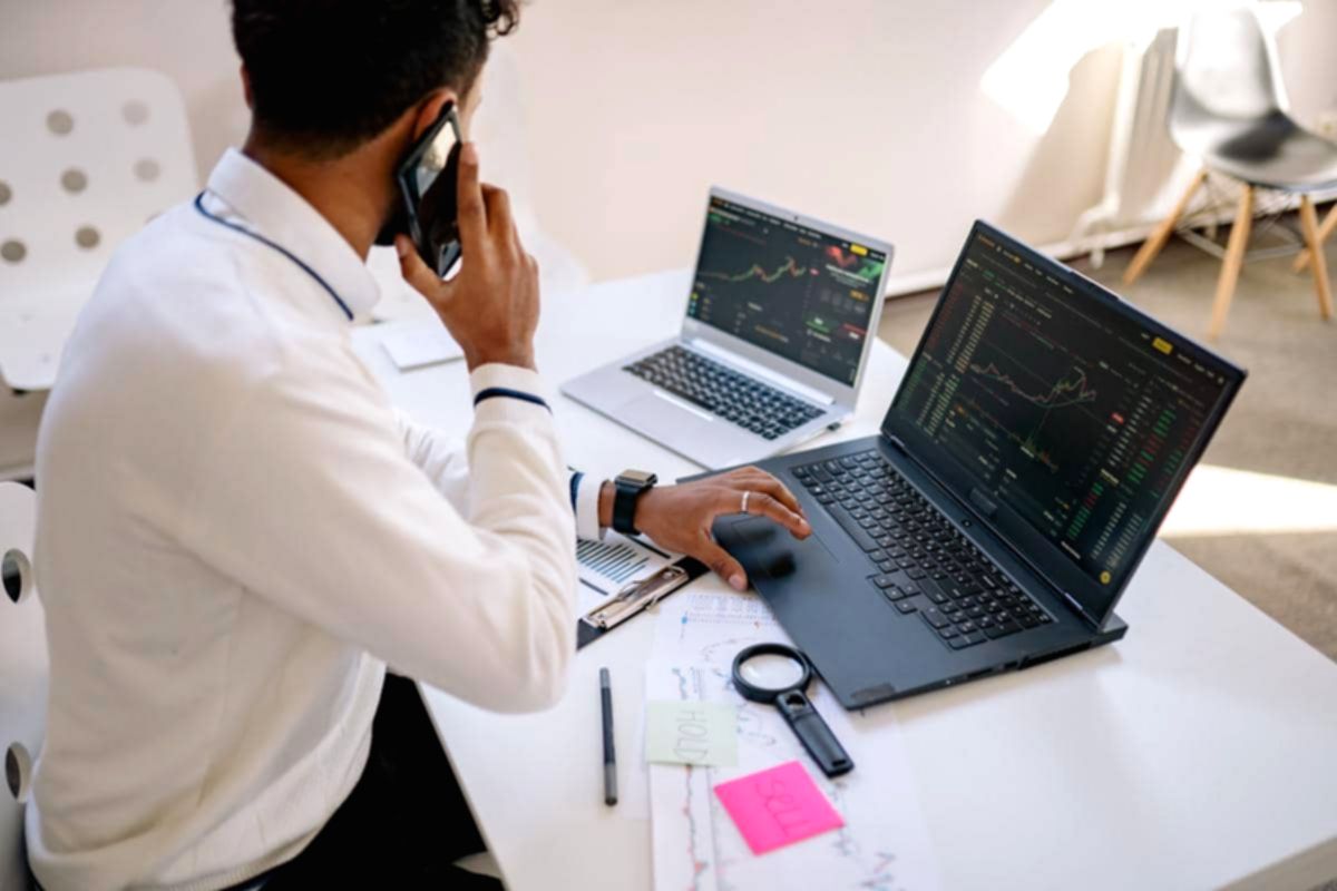 Seorang investor sedang menganalisis grafik pergerakan harga saham di laptop untuk menentukan nilai wajar investasi